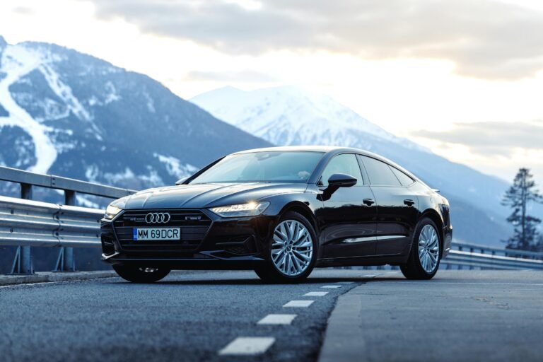 Elegant black car on mountain road with stunning snow-covered peaks in Romania.